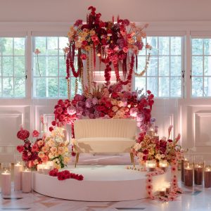 Elegant sangeet decor / ceremony backdrop decorated with vibrant drapes, fairy lights, and floral arrangements
