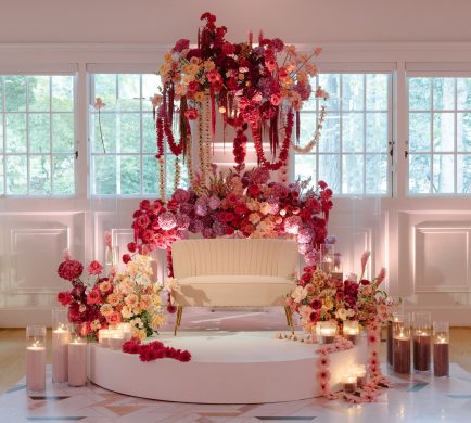 Elegant sangeet decor / ceremony backdrop decorated with vibrant drapes, fairy lights, and floral arrangements